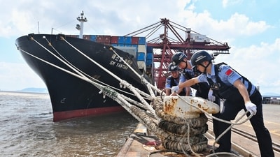 Police officers check the mooring lines of a vessel ahead of Typhoon Dolphin in Beilun District of Ningbo City, east China's Zhejiang Province, on Friday. (File Photo/AP)