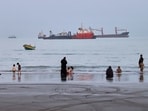 People spend time at a beach as commercial vessels are anchored in the Strait of Hormuz off Bandar Abbas, Iran.