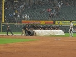 The Chicago White Sox grounds crew rolls out the tarp during a rain delay in the second inning of a baseball game against the Cleveland Guardians.
