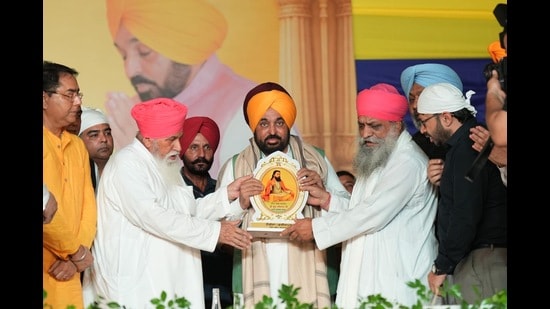 Dera Sachkhand Ballan spiritual head Sant Niranjan Dass (left) presenting a memento to Punjab chief minister Bhagwant Mann in Jalandhar on Sunday. (HT)
