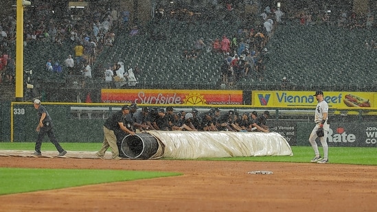 The Chicago White Sox grounds crew rolls out the tarp during a rain delay in the second inning of a baseball game against the Cleveland Guardians.(AP Photo/Melissa Tamez)