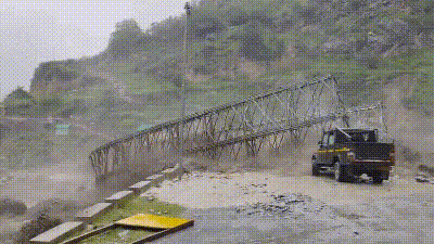 A video of the incident shows a powerful surge of muddy water rushing through the valley and hitting the metal bridge. (HT sourced)
