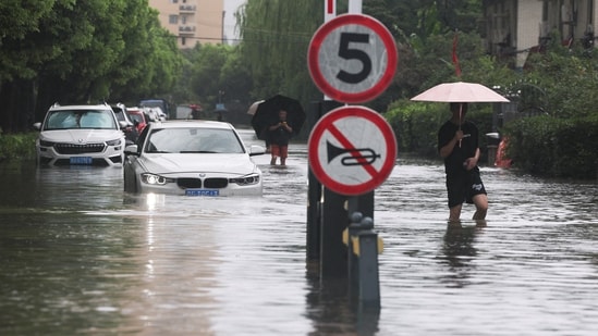 People wade through a flooded street after Typhoon Dolphin brought heavy rain to Shanghai, China.