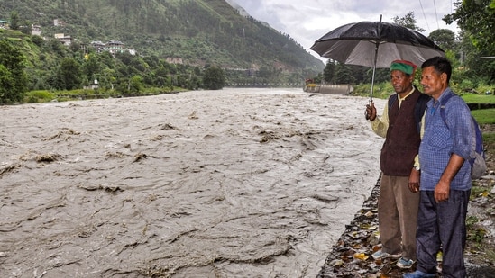 People look at the swollen Beas river as the water level rises following incessant monsoon rain, in Kullu, Himachal Pradesh.