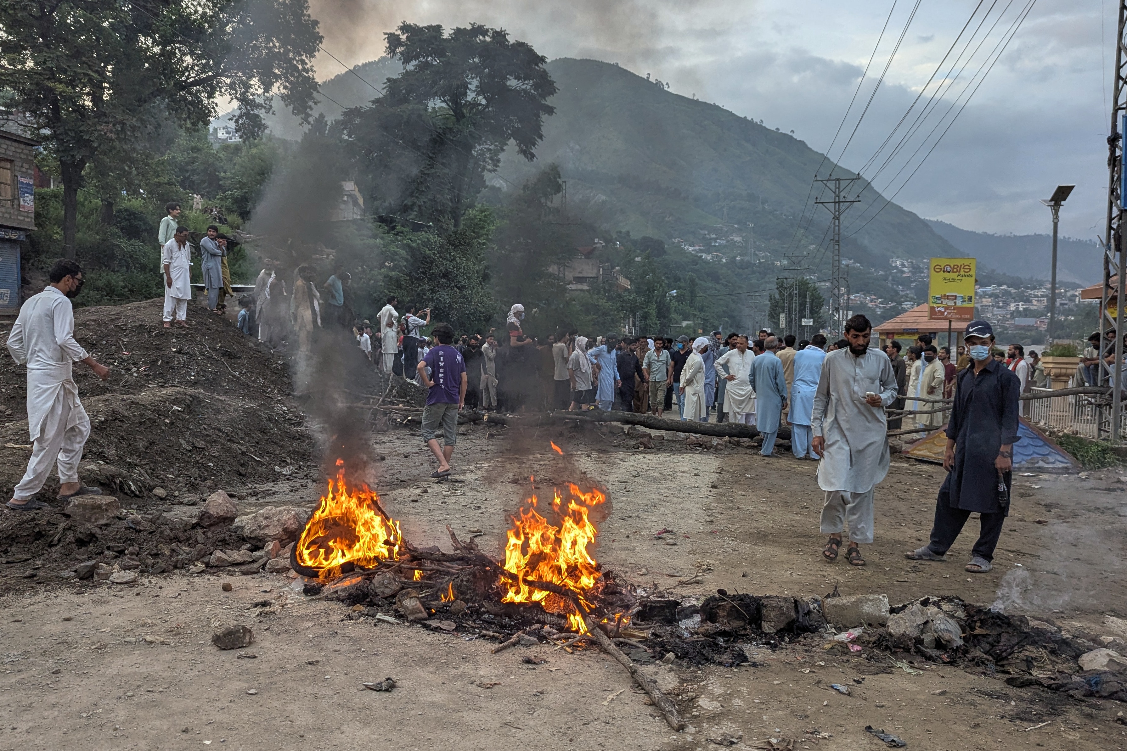 Supporters of the outlawed Joint Awami Action Committee (JAAC) block a road with a burning barricade after clashes with police during a protest demanding greater political rights and the abolition of 12 legislative refugee seats, in Muzaffarabad, the capital of PoK. (AP ) Supporters of the outlawed Joint Awami Action Committee (JAAC) block a road with a burning barricade after clashes with police during a protest demanding greater political rights and the abolition of 12 legislative refugee seats, in Muzaffarabad, the capital of PoK. (AP )