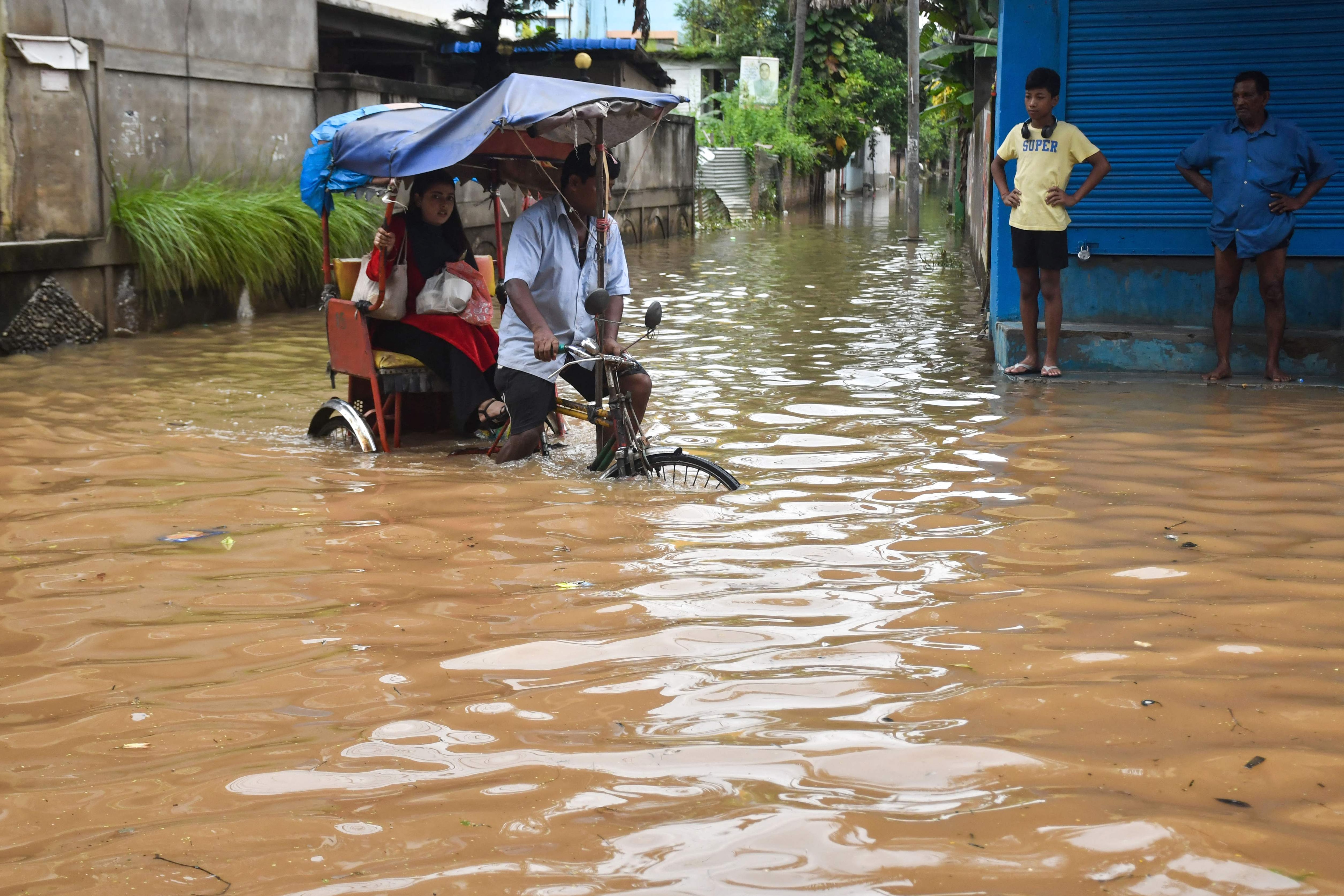 A resident commutes in a cycle rickshaw through a flooded street following heavy rainfall in Guwahati on August 9, 2026. Floods in India's northeast have killed nearly 100 people, according to an official toll update on August 7, with villages buried in mud after one of Assam state's worst deluges in years. (AFP)