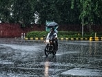 A commuter on a two-wheeler passes through a rain-slicked road amid heavy rainfall, in New Delhi.