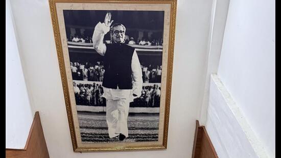 In the black-and-white photograph, Sheikh Mujibur Rahman is raising a hand in greeting.