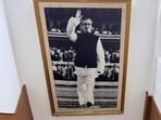 In the black-and-white photograph, Sheikh Mujibur Rahman is raising a hand in greeting.
