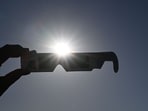 A woman holds a pair of eclipse glasses in front of the sun in Salzburg, Austria on August 12 ahead of the partial solar eclipse.