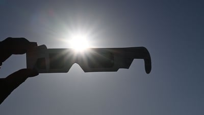 A woman holds a pair of eclipse glasses in front of the sun in Salzburg, Austria on August 12 ahead of the partial solar eclipse. (AFP) A woman holds a pair of eclipse glasses in front of the sun in Salzburg, Austria on August 12 ahead of the partial solar eclipse. (AFP)
