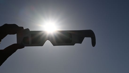 A woman holds a pair of eclipse glasses in front of the sun in Salzburg, Austria on August 12 ahead of the partial solar eclipse.
