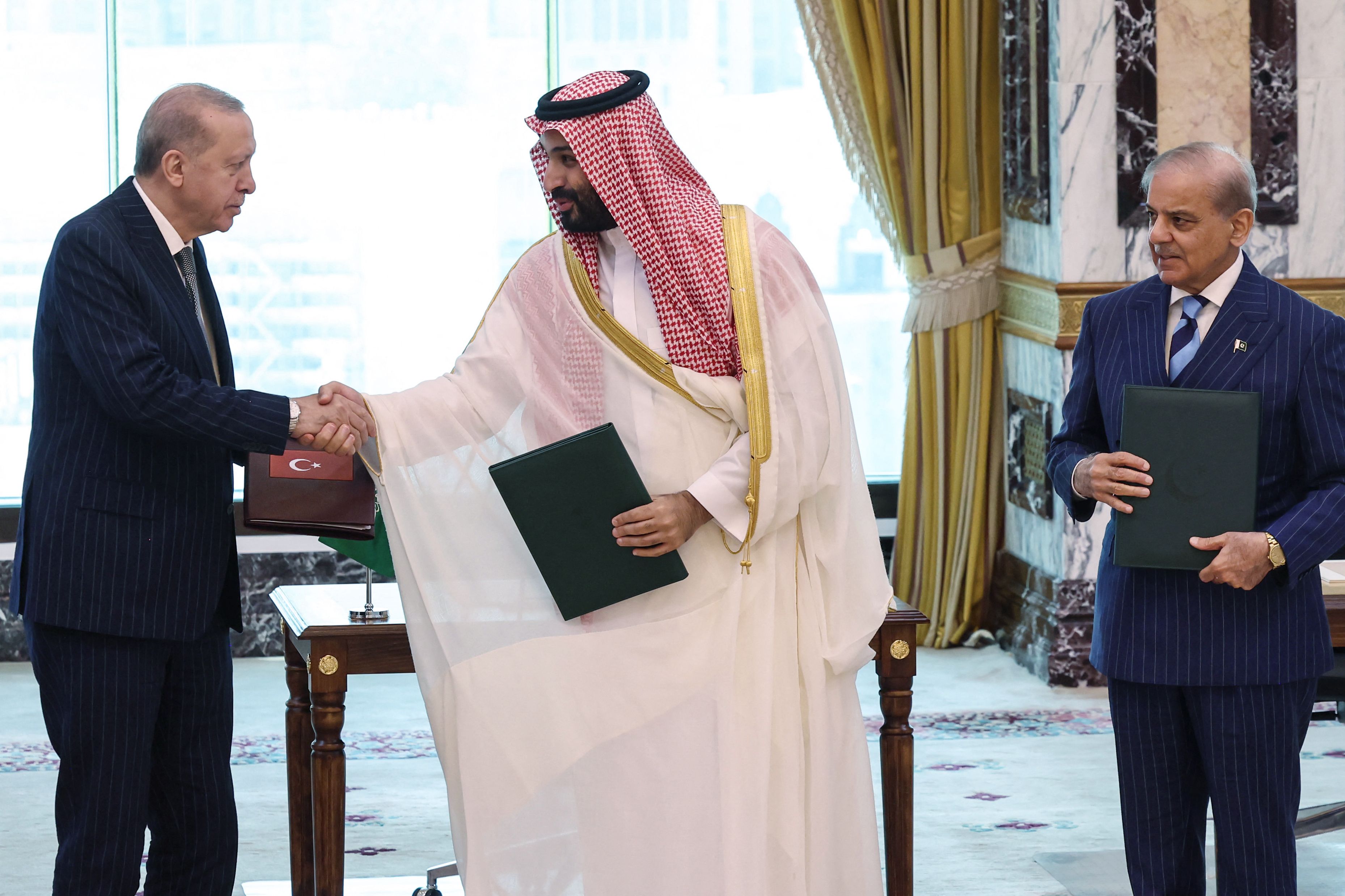 Turkey's President Recep Tayyip Erdogan (L) shaking hands with Saudi Arabia's Crown Prince Mohammed bin Salman as Pakistan's Prime Minister Shehbaz Sharif looks on after signing a joint defence agreement in Mecca. Saudi Arabia, Turkey and Pakistan signed a joint defence agreement on August 7. (AFP) Turkey's President Recep Tayyip Erdogan (L) shaking hands with Saudi Arabia's Crown Prince Mohammed bin Salman as Pakistan's Prime Minister Shehbaz Sharif looks on after signing a joint defence agreement in Mecca. Saudi Arabia, Turkey and Pakistan signed a joint defence agreement on August 7. (AFP)