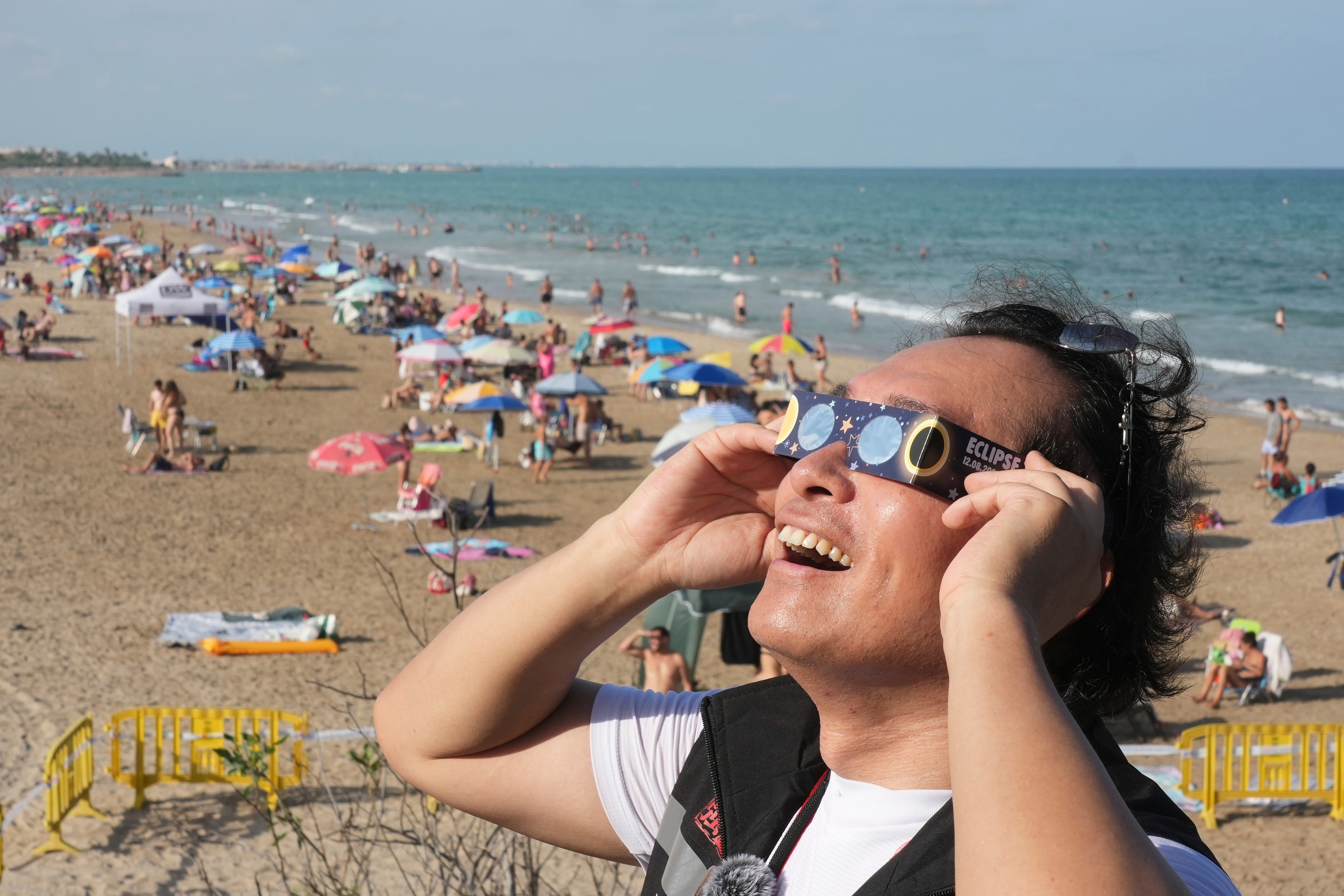 A man wears special eclipse glasses, as beachgoers gather before a total solar eclipse set to begin around sunset, at a beach near Valencia, Spain, (AP Photo/Alberto Saiz) A man wears special eclipse glasses, as beachgoers gather before a total solar eclipse set to begin around sunset, at a beach near Valencia, Spain, (AP Photo/Alberto Saiz)