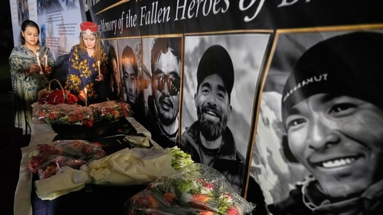 Woman place candles next to pictures of climbers who lost their lives on Broad Peak, during a candlelight vigil in their memory, in Islamabad, Pakistan, Tuesday, Aug. 11, 2026. (AP Photo/Anjum Naveed)