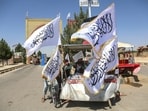 An Afghan boy buys a Taliban flag from a roadside vendor in Afghanistan's Ghazni province on August 14, 2026 ahead of the fifth anniversary of the Taliban government's return to power.