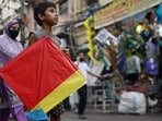A child carries a kite across a market in the old quarters of Delhi on August 11, 2026.