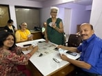 Pushpa Singh stands by the table for a quick photo, holding her cards in a fan.
