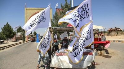 An Afghan boy buys a Taliban flag from a roadside vendor in Afghanistan's Ghazni province on August 14, 2026 ahead of the fifth anniversary of the Taliban government's return to power. (AFP)