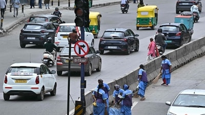 File image: Sanitation workers clean a roadside median as traffic moves along a road in Bengaluru (AFP) File image: Sanitation workers clean a roadside median as traffic moves along a road in Bengaluru (AFP)