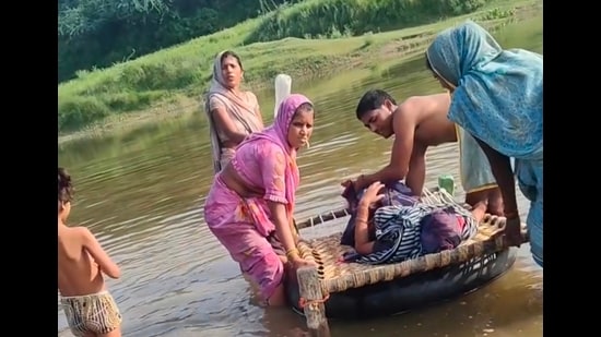 Woman and her newborn being carried across the Utangan river in Agra district on Thursday. (HT Photo)