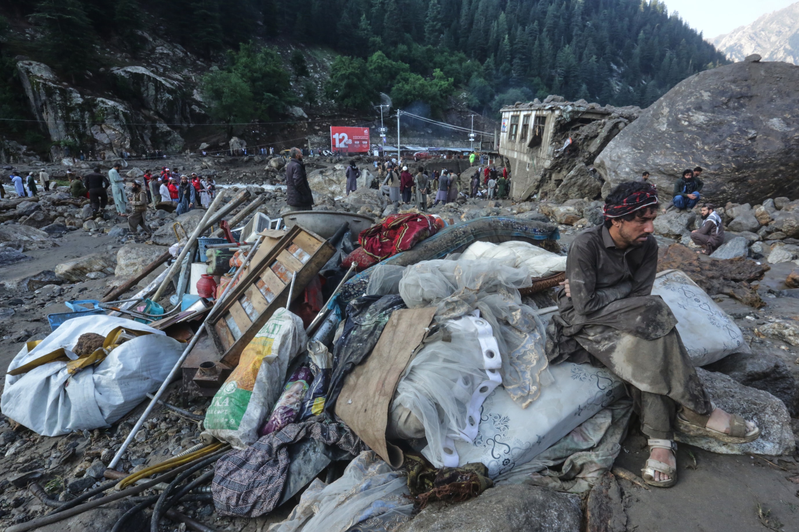 A man sits beside salvaged belongings following heavy flooding in the eastern province of Nuristan, Afghanistan, July 21, 2026. (AP Photo/Wahidullah Kakar)