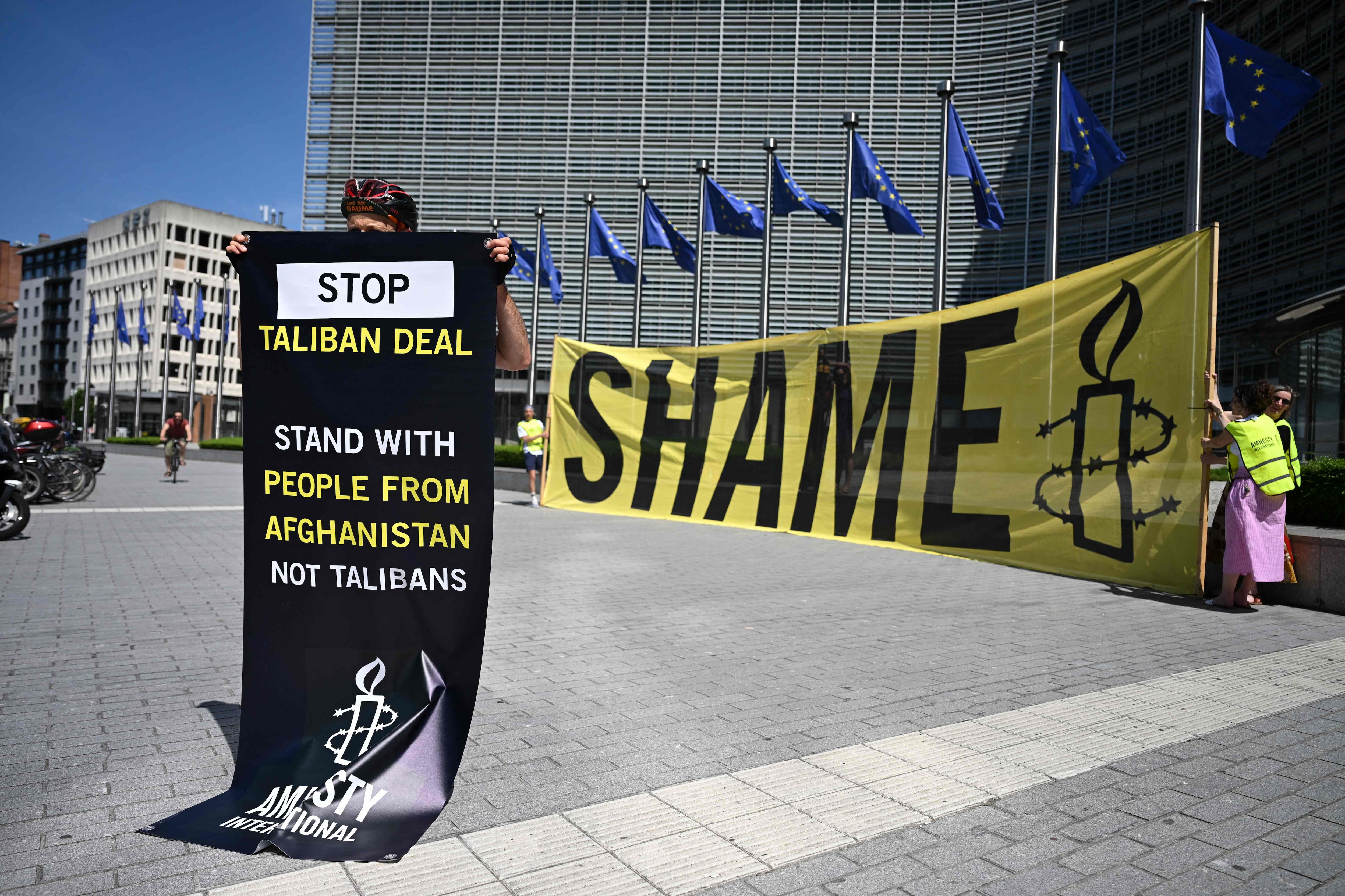 An Amnesty International activist hold a banner reading 'Stop Taliban deal' in front of the EU Commission headquarters to protest against a meeting with a Taliban delegation in Brussels on June 23, 2026. (AFP)