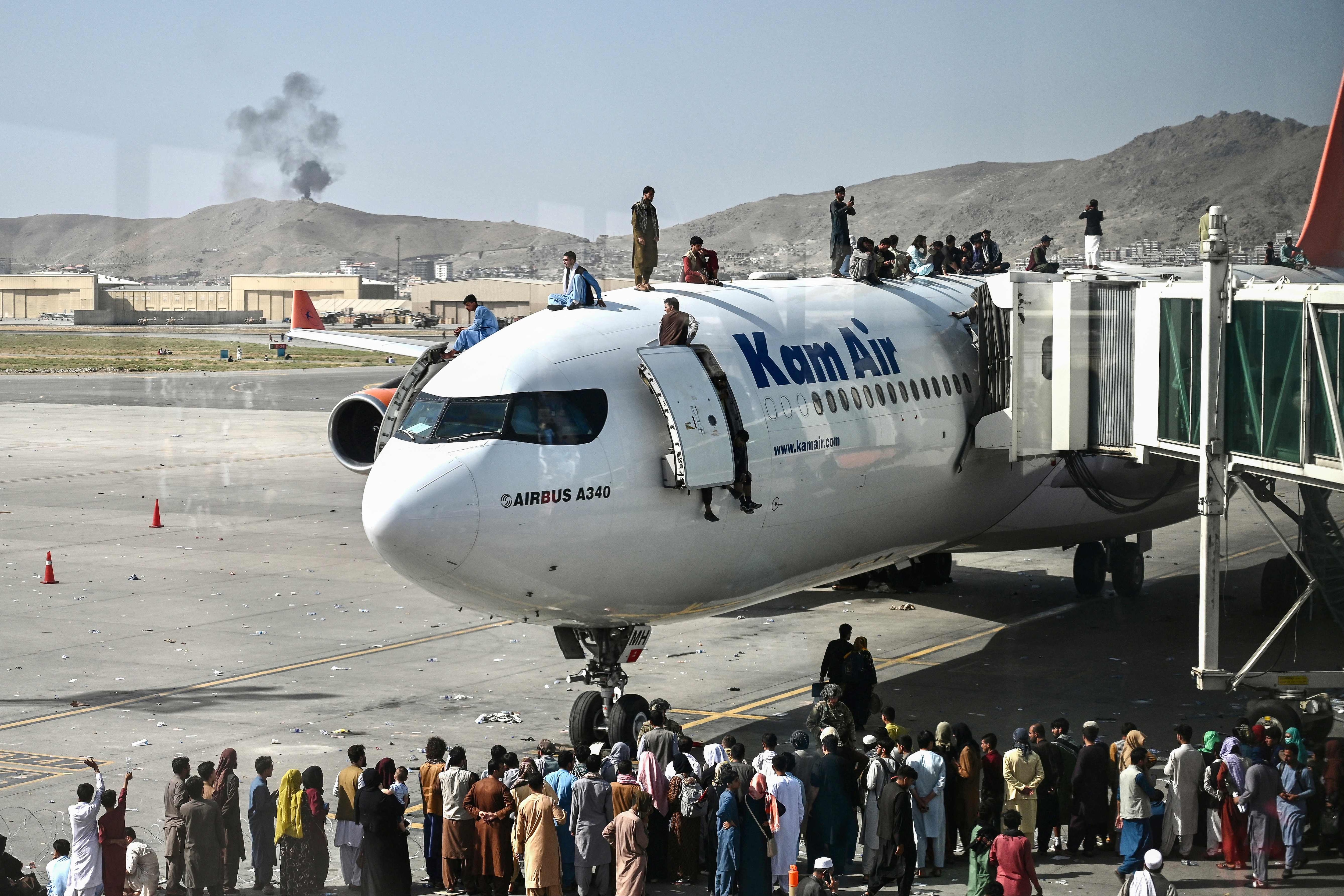 Afghan people climb atop a plane as they wait at the Kabul airport in Kabul on August 16, 2021, as thousands of people swarmed the city's airport trying to flee the Taliban. Taliban forces captured the Afghan capital Kabul on August 15, 2021, prompting their return to power after Washington's decision to withdraw US troops from the country. (AFP File)