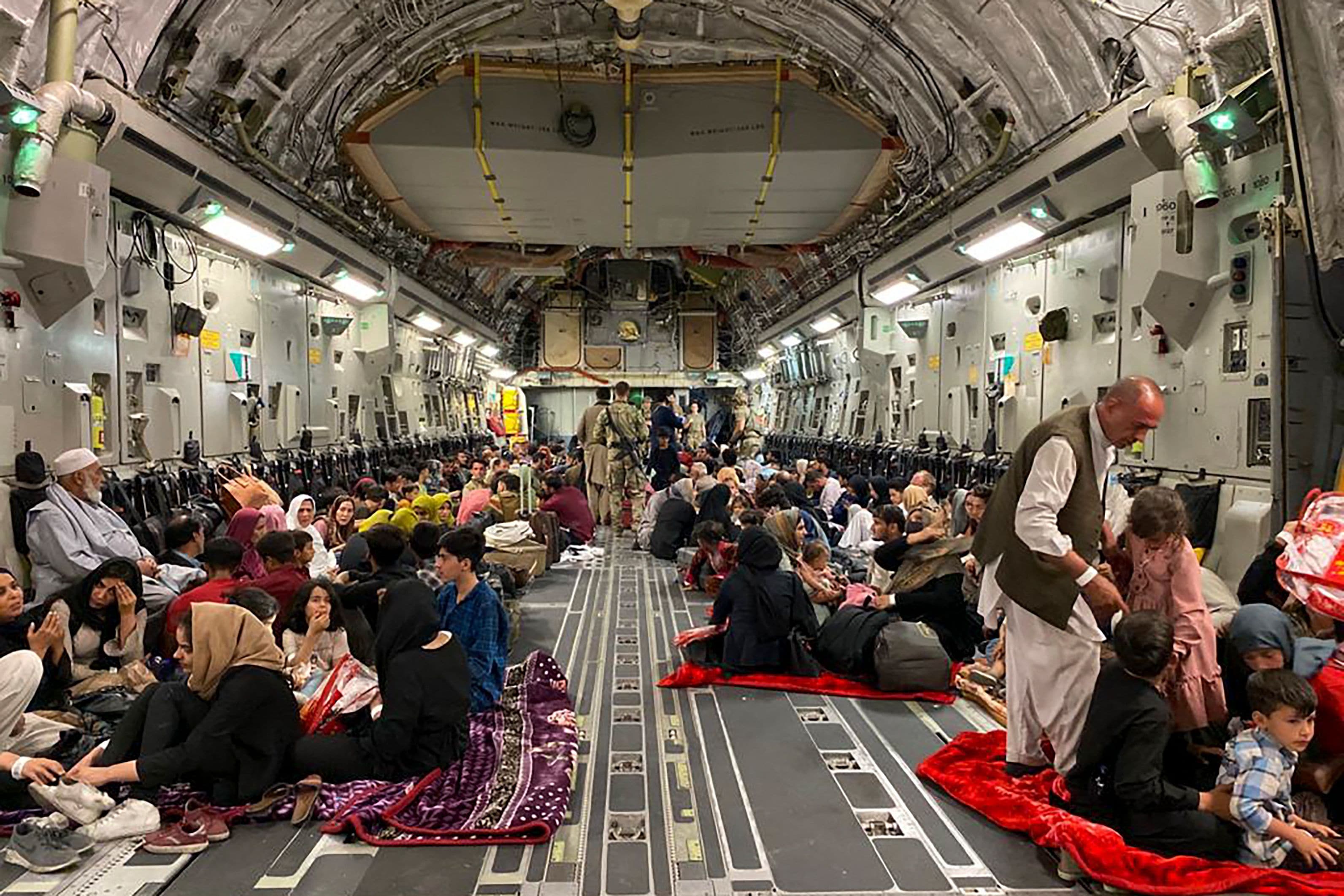 Afghan people sit inside a US military aircraft to leave Afghanistan, at the military airport in Kabul on August 19, 2021. (AFP)
