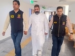 Fugitive drug kingpin Virender Singh Basoya, in white, being escorted by Narcotics Control Bureau (NCB) personnel as he is produced before the Rouse Avenue court, in New Delhi.