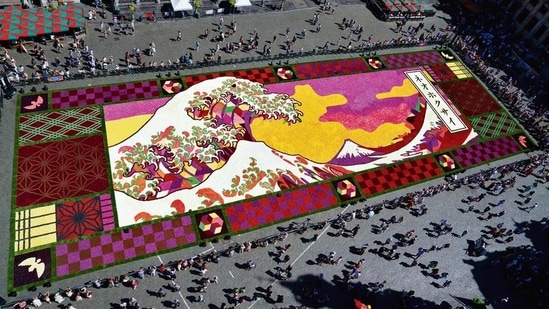 An overview of a giant flower carpet inspired by The Great Wave off Kanagawa by Japanese artist Katsushika Hokusai at the historic Grand Place in Brussels,