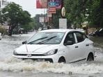 A car wades through a waterlogged road in Lucknow’s Aliganj area on Sunday. (Deepak Gupta/HT)
