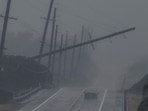 A vehicle drives near a downed utility pole dangling above Mamalahoa Highway during Hurricane Lala near Ocean View, Hawaii.