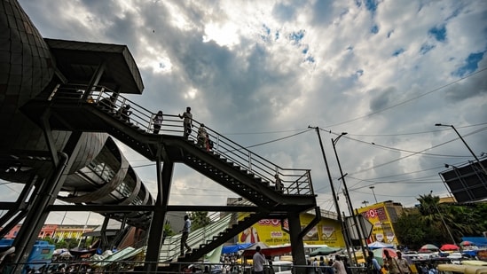 People walk under a monsoon sky outside the New Delhi railway station in New Delhi.