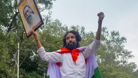 Ranchi: Student leader Devendra Nath Mahto, wrapped in the national flag, holds a portrait of Jharkhand Mukti Morcha (JMM) chief Shibu Soren. (PTI File)