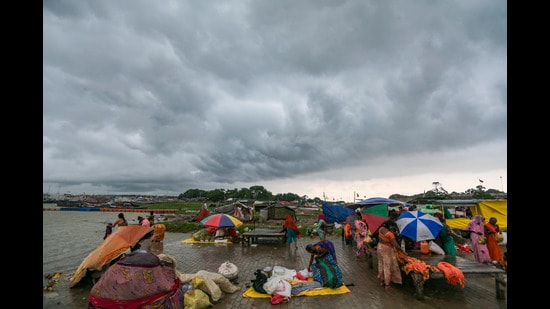 People arrange shelters and umbrellas amid dark monsoon clouds, at Sangam in Prayagraj, Tuesday (PTI)