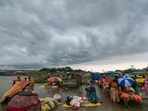 People arrange shelters and umbrellas amid dark monsoon clouds, at Sangam in Prayagraj, Tuesday (PTI)