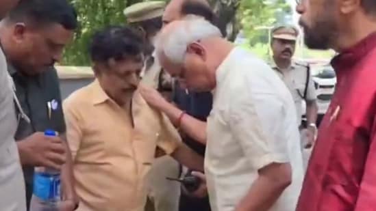 Kerala governor Rajendra Vishwanath Arlekar (in white shirt) helping the man (in yellow shirt) who fainted outside the Kerala Lok Bhavan.