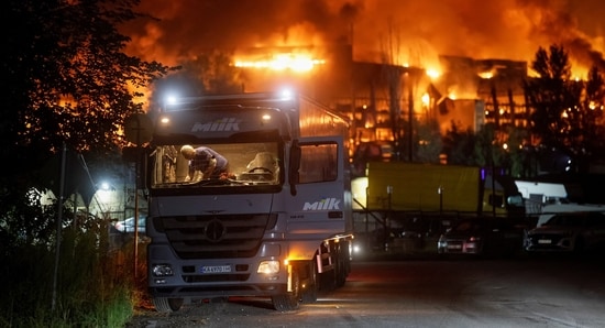 A wounded driver cleans broken glass in the cabin of a damaged truck at the site of the building of a supermarket warehouse hit by a Russian missile strike, amid Russia's attack on Ukraine, in Kyiv, Ukraine, August 5, 2026. (REUTERS/Gleb Garanich)