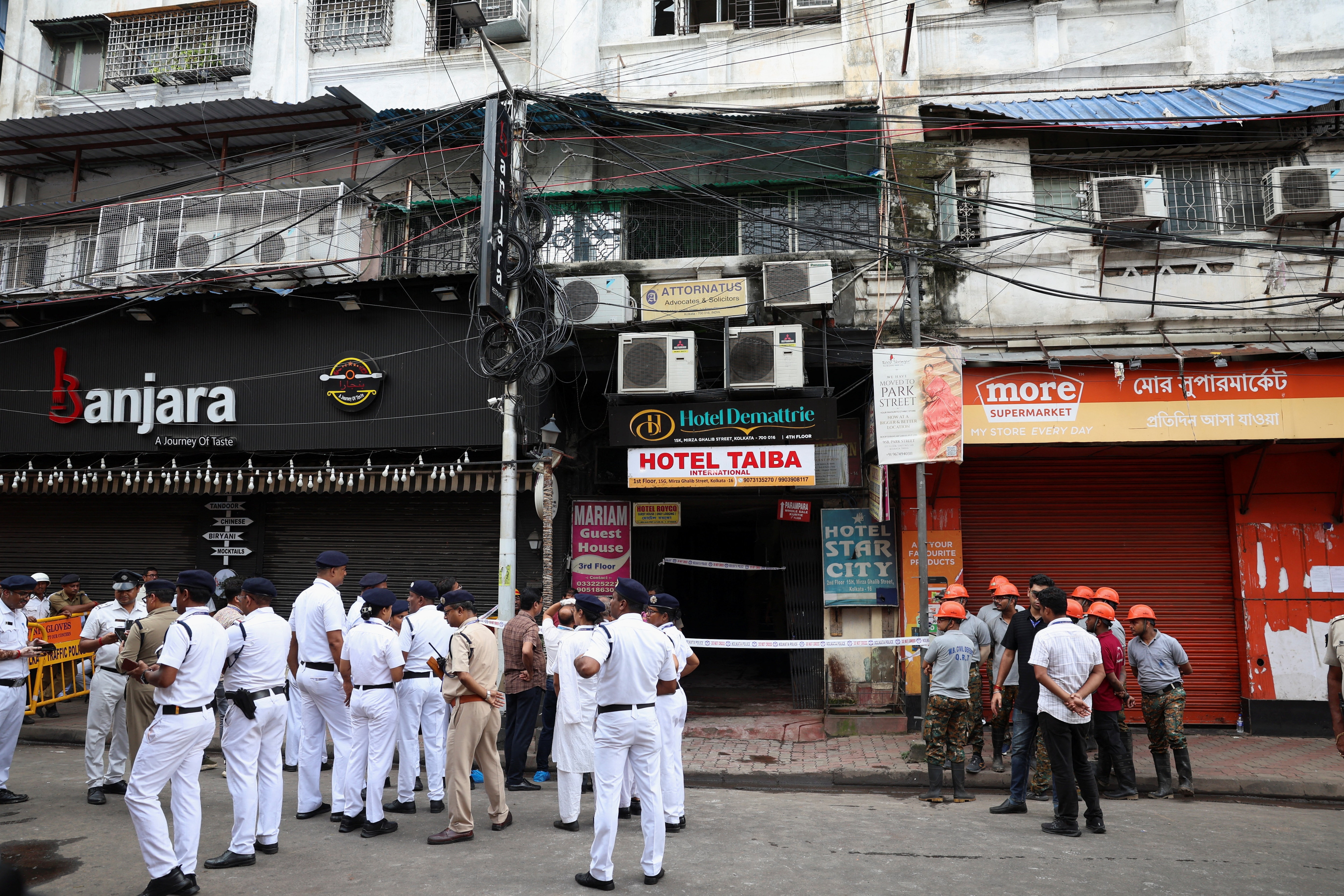 Firefighters and other officials stand on the street in the aftermath of hotel a fire that killed several people in Kolkata, India (REUTERS)