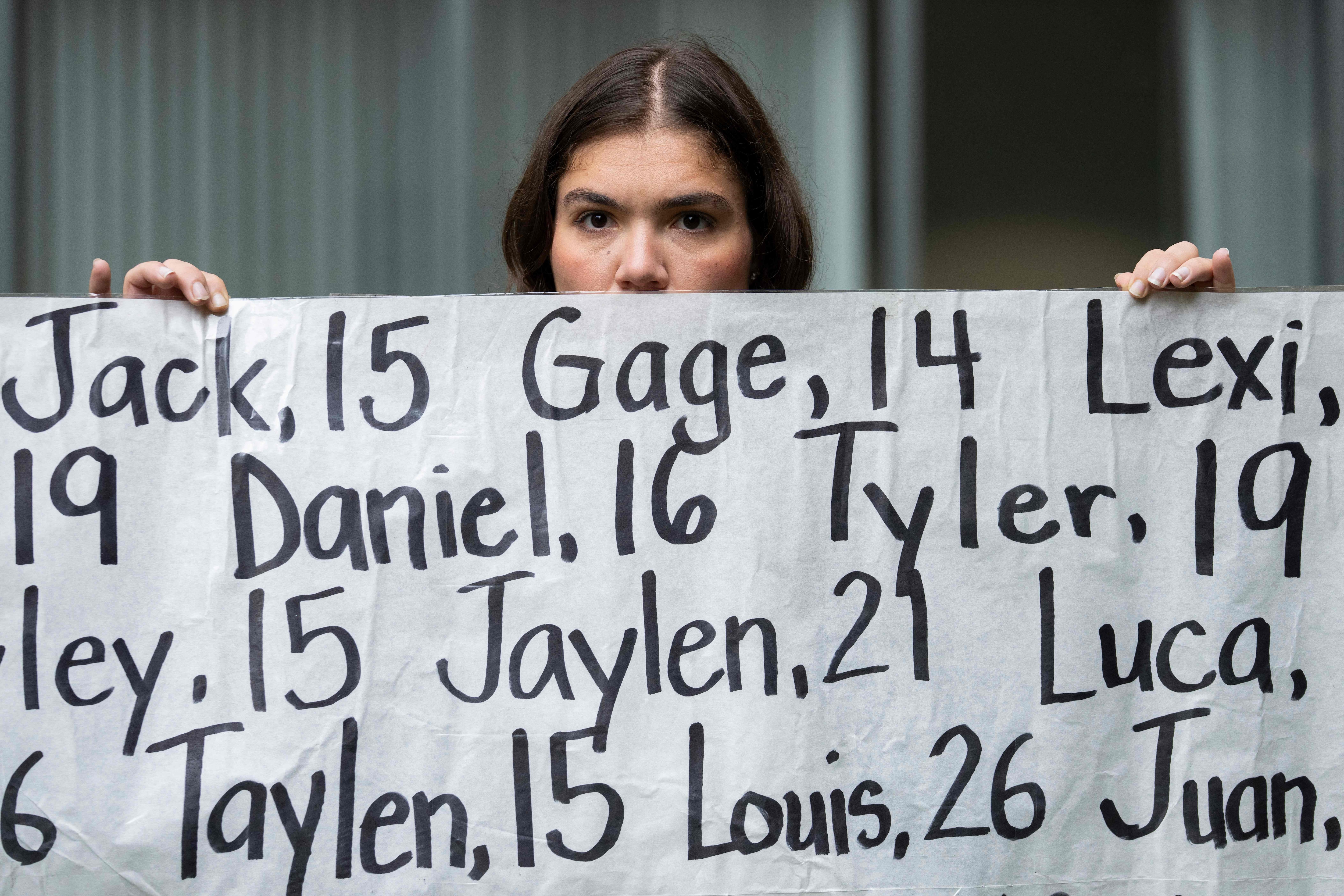 TOPSHOT - Olivia Konar holds a banner with the names of nearly 400 young people who allegedly died from the impacts of social media outside the Ronald V. Dellums Federal Building & United States Courthouse in Oakland, California, on August 18, 2026, as opening arguments begin in the Meta trial over a lawsuit brought by US states about social media addiction. A coalition of US states is seeking around $200 billion in damages against Meta, which they accuse of intentionally designing Facebook and Instagram to be addictive for children. Meta previously had claimed in court documents that the financial penalties could reach $1.4 trillion, close to its entire market value which hovers around $1.5 trillion. (Photo by Godofredo A. V�SQUEZ / AFP) (AFP)
