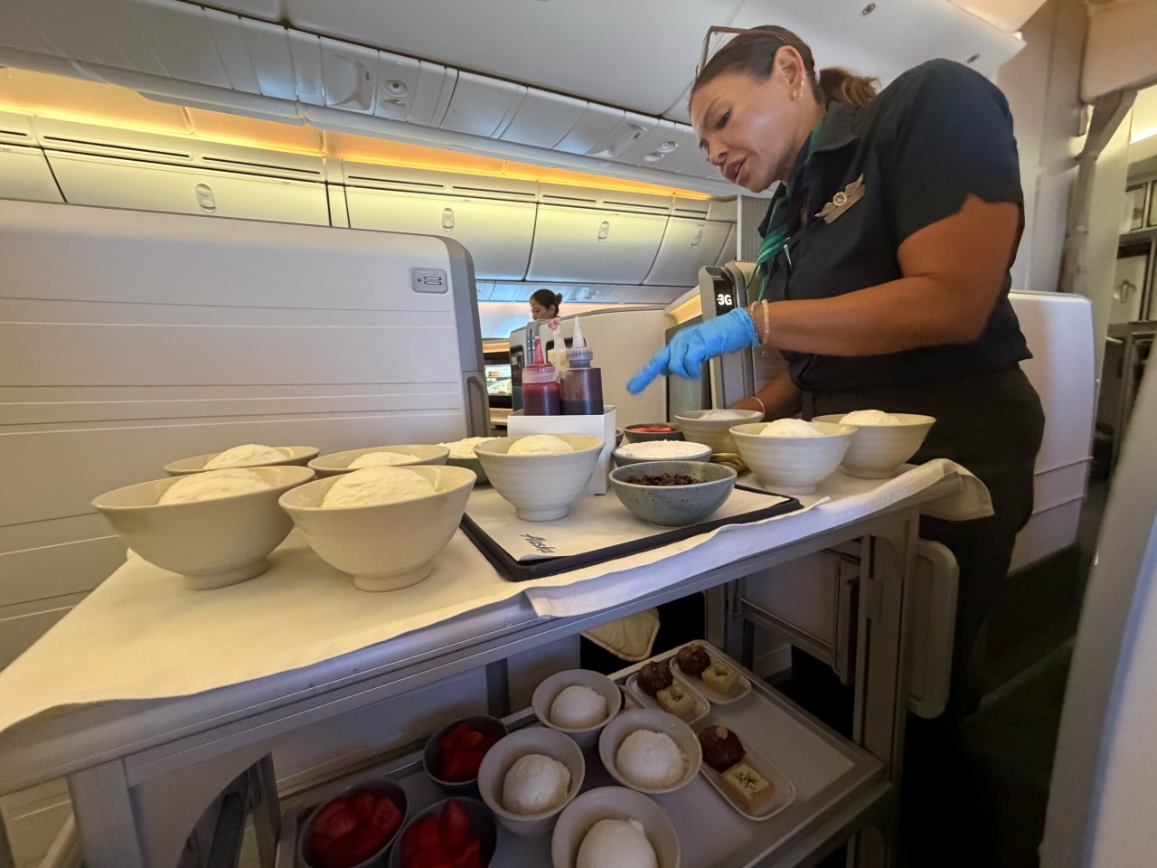 Flight attendants make custom ice cream sundaes for passengers after dinner. Flight attendants make custom ice cream sundaes for passengers after dinner.