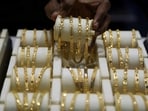 A salesman arranges gold bangles inside a jewellery showroom.