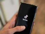 This photograph shows a man holding a smartphone displaying the logo of Chinese social media platform Tiktok in an office in Paris.(AFP)