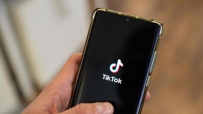This photograph shows a man holding a smartphone displaying the logo of Chinese social media platform Tiktok in an office in Paris. (AFP)