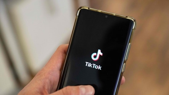 This photograph shows a man holding a smartphone displaying the logo of Chinese social media platform Tiktok in an office in Paris.