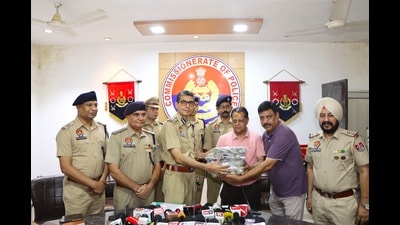 Jalandhar commissioner of police Satinder Singh handing over the recovered money to the robbery victim. (HT) Jalandhar commissioner of police Satinder Singh handing over the recovered money to the robbery victim. (HT)