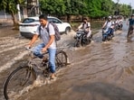 Commuters wade through a waterlogged road following heavy rain, in Gurugram, Haryana, Saturday, Aug. 22, 2026. (PTI)