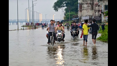 Commuters move on an inundated area following the rise of water level in the Ganga river at low lying area of Daraganj in Prayagraj on Sunday (PTI)