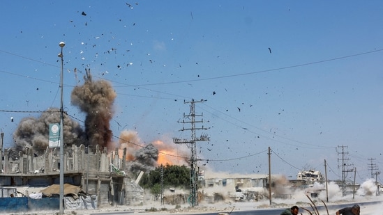 People run for cover, as debris flies through the air, during an Israeli strike, carried out after the Israeli military warned residents to evacuate the area, Al-Zawayda, in the central Gaza Strip, 